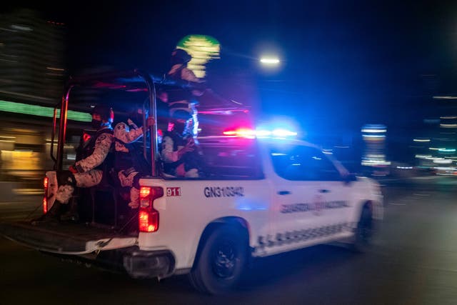 Miembros armados de la Guardia Nacional pasan por el lugar de un vehículo de transporte colectivo quemado luego de que individuos no identificados lo incendiaran en Tijuana, estado de Baja California, México, el 12 de agosto de 2022