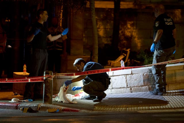 Los investigadores de la escena del crimen de la policía israelí trabajan en la escena de un ataque a tiros que hirió a varios israelíes cerca de la Ciudad Vieja de Jerusalén, la madrugada del domingo 14 de agosto de 2022.