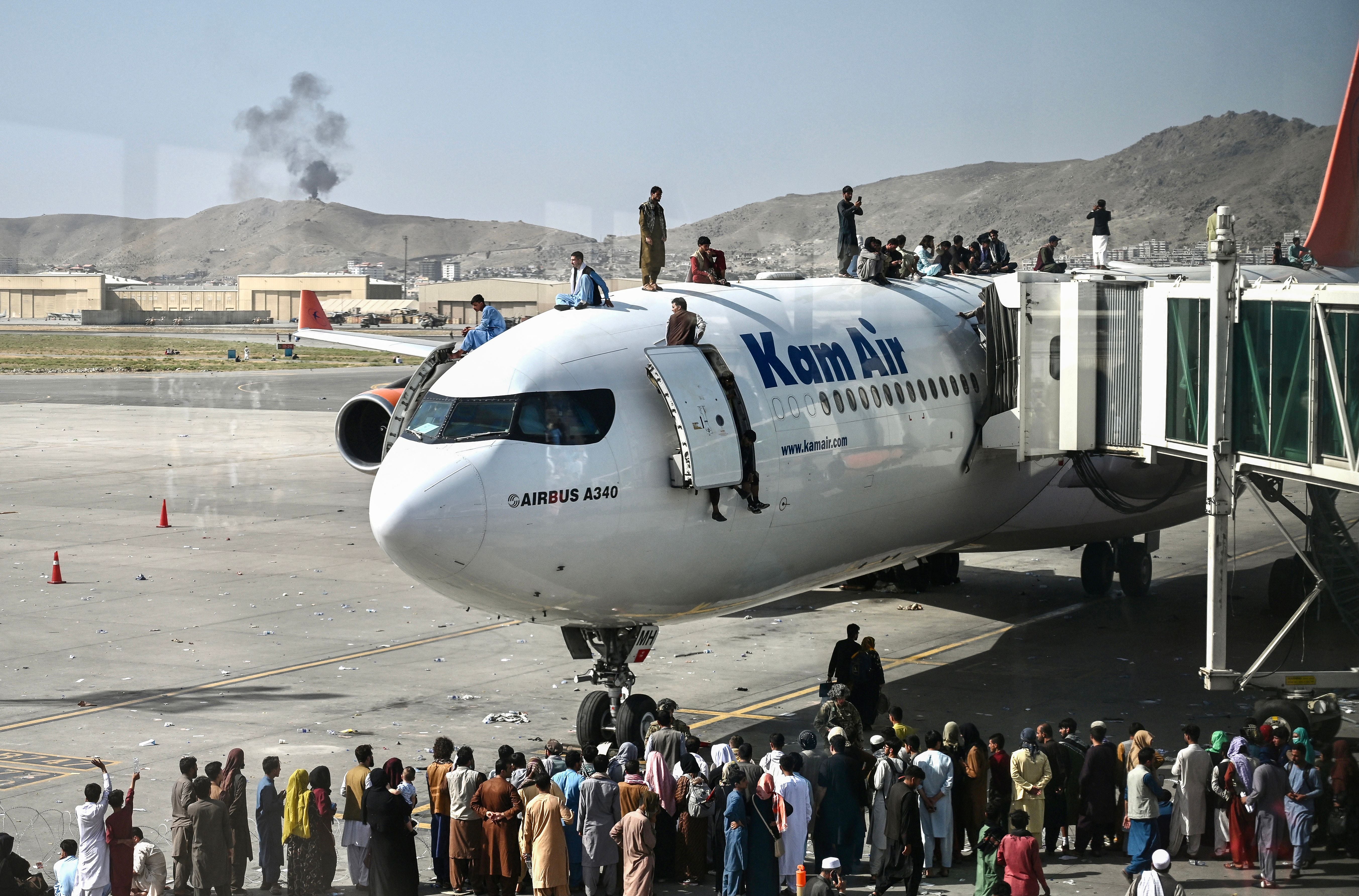Desperate people climb on top of a plane at Kabul airport on 16 August 16, 2021, after a stunningly swift end to Afghanistan's 20-year war