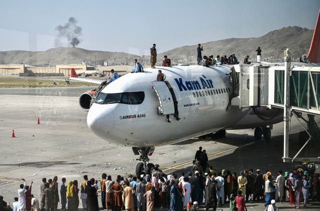 <p>Desperate people climb on top of a plane at Kabul airport on 16 August 16, 2021, after a stunningly swift end to Afghanistan's 20-year war</p>