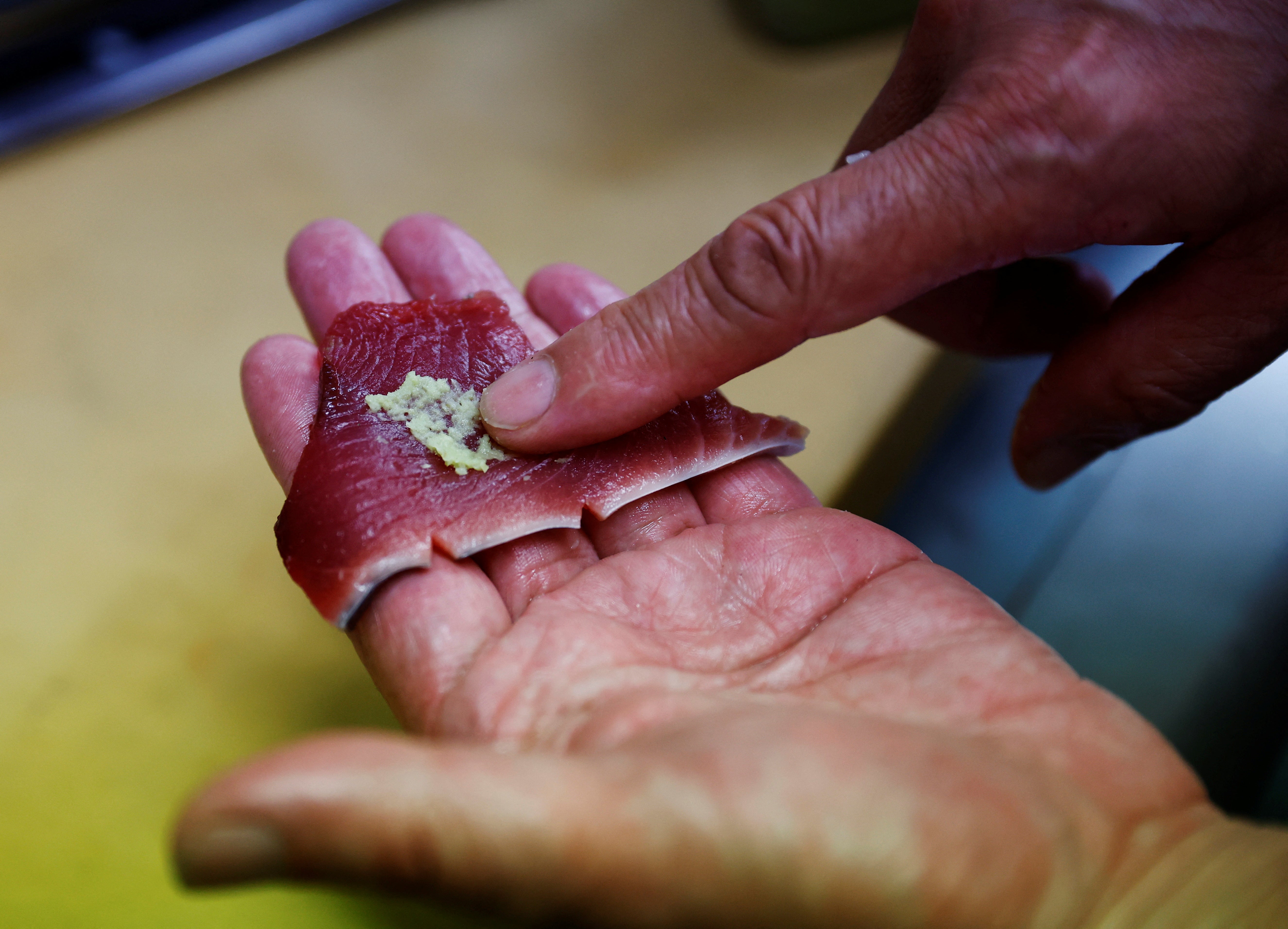 Noriaki Ito, head chef of 106 year-old restaurant Tsukasa, puts wasabi on a piece of raw katsuo (skipjack tuna), in Kochi