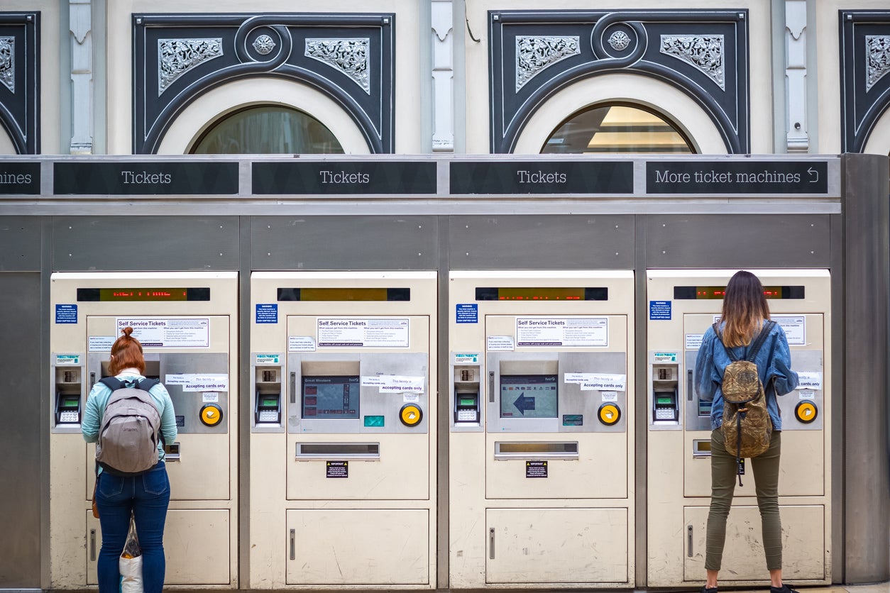 Passengers buying train tickets from machines at London Paddington station