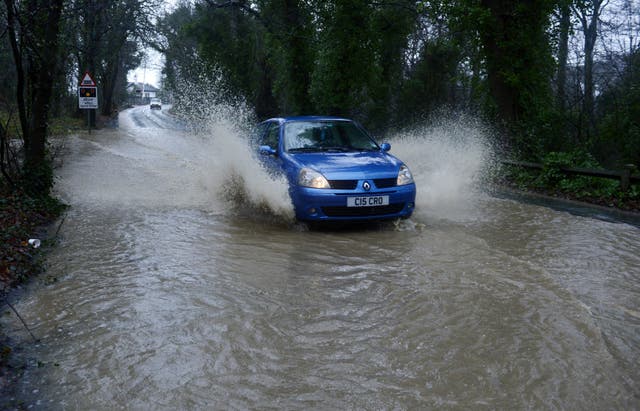 A car drives through flood water (PA)