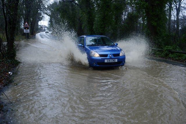 A car drives through flood water (PA)