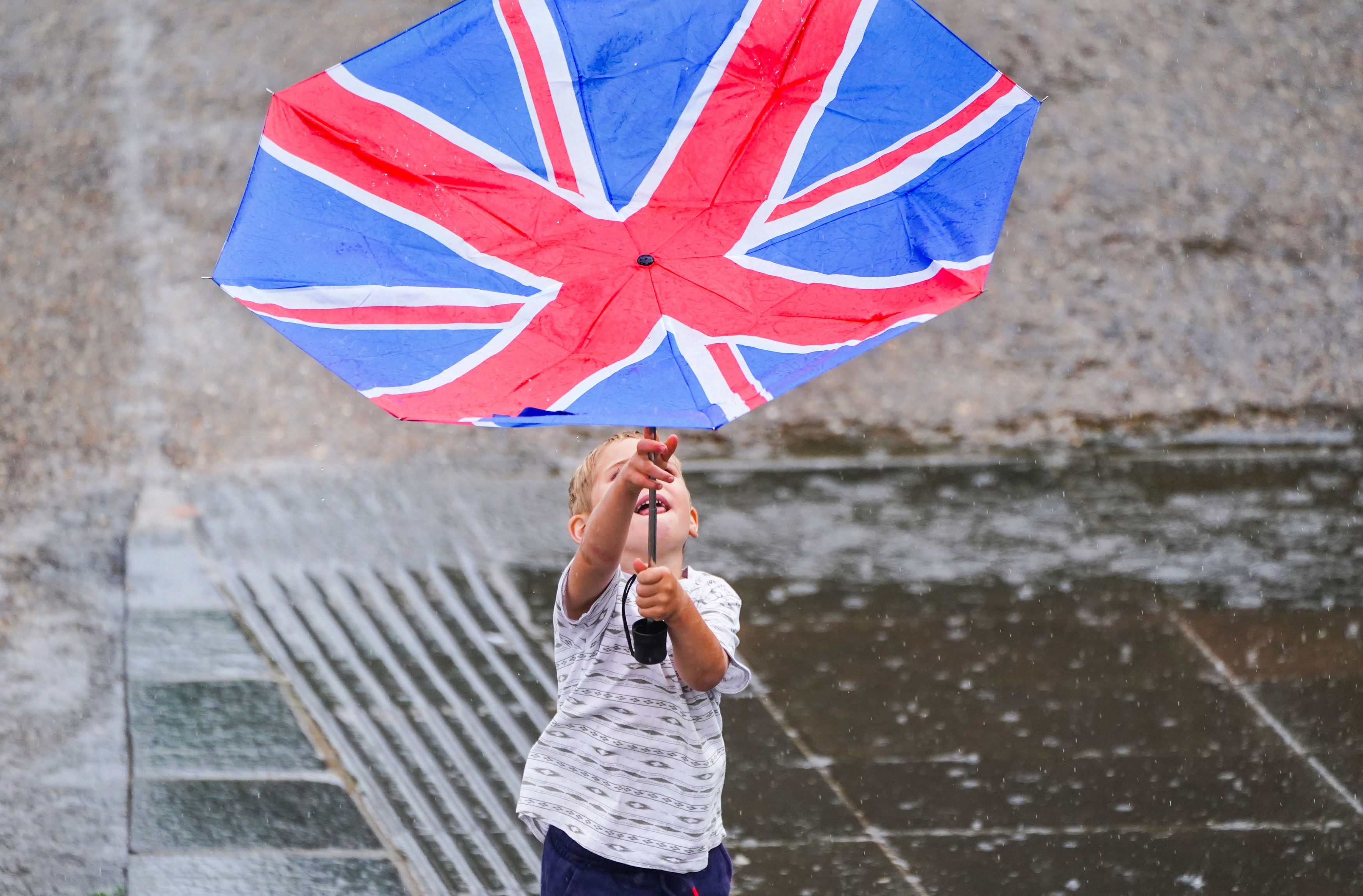 A young boy battles with an umbrella on the South Bank