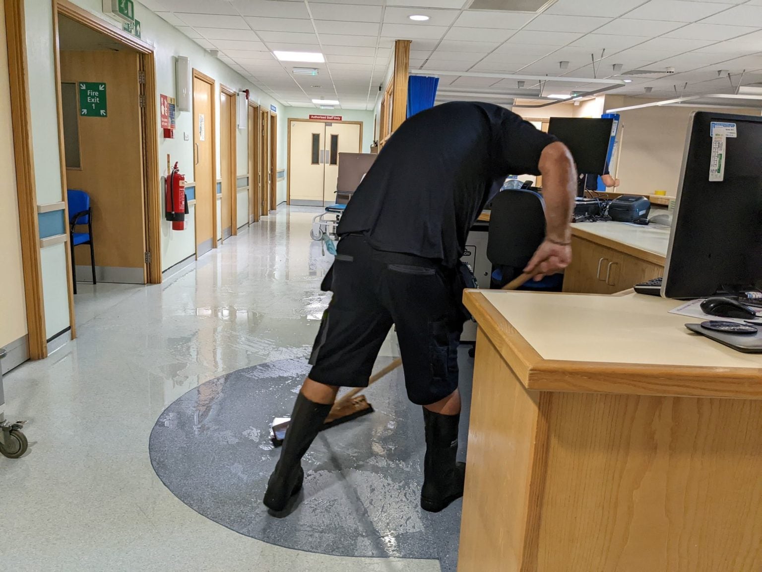 Hospital worker sweeps flooddwater from the building