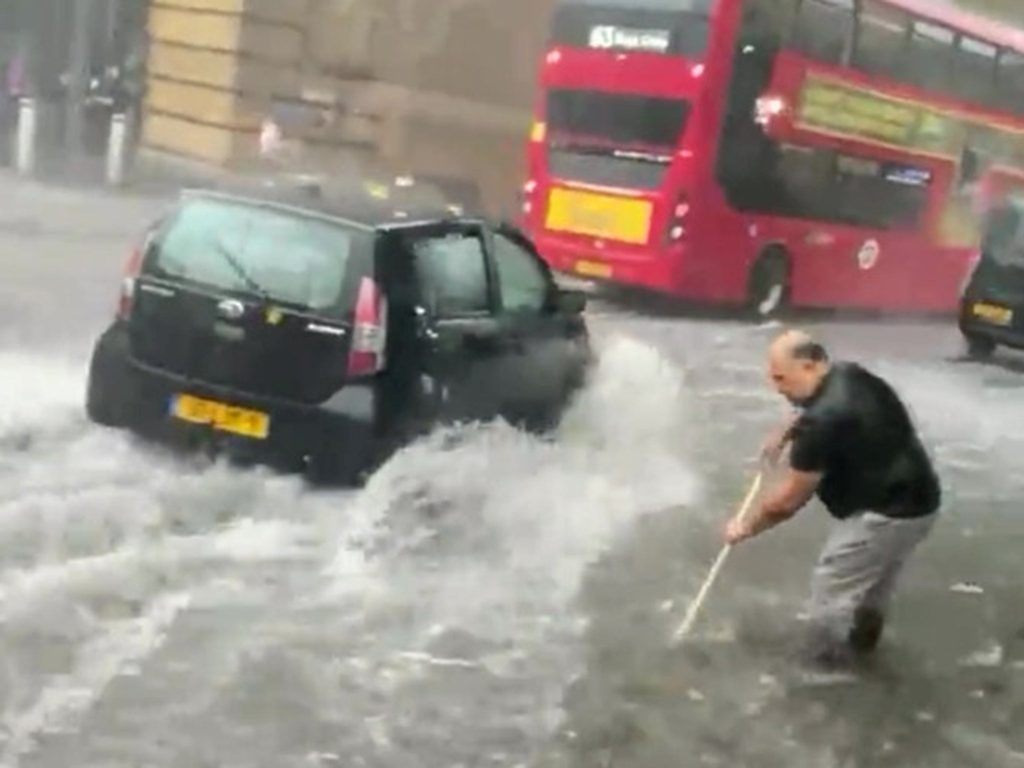 A man tries to sweep a drain near Kings Cross station