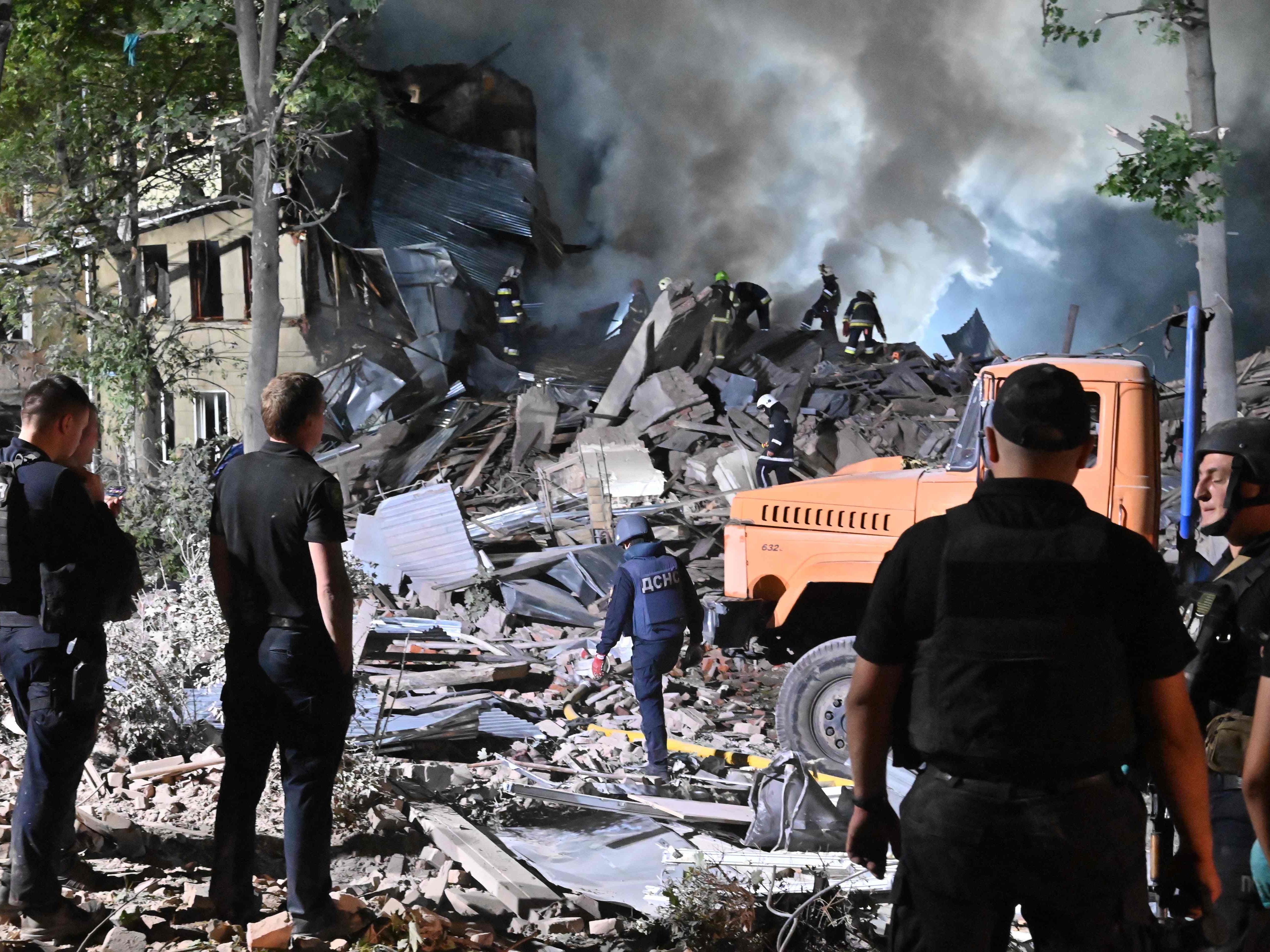 Rescue workers inspect the site of a destroyed hostel in Kharkiv