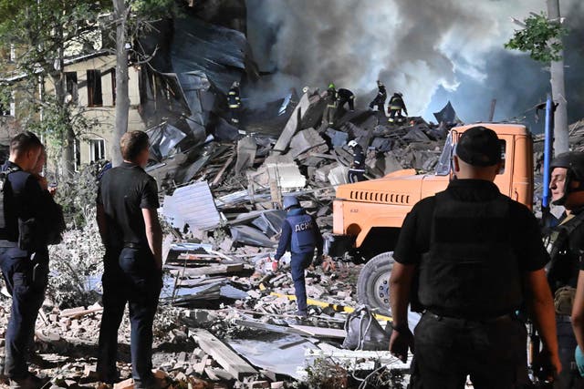 <p>Rescue workers inspect the site of a destroyed hostel in Kharkiv</p>