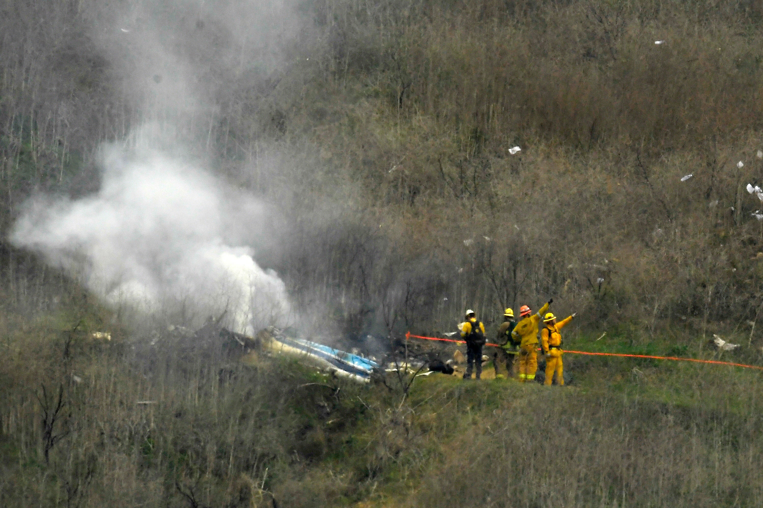 FILE - Firefighters work the scene of a helicopter crash where former NBA basketball star Kobe Bryant died in Calabasas, Calif., Jan. 26, 2020.
