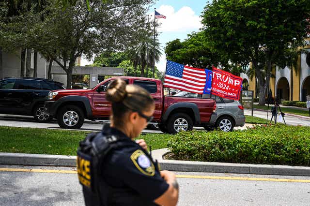 Supporters of former US President Donald Trump drive around the Paul G. Rogers Federal Building & Courthouse as the court holds a hearing to determine if the affidavit used by the FBI as justification for last week's search of Trump's Mar-a-Lago estate should be unsealed, at the US District Courthouse for the Southern District of Florida in West Palm Beach, Florida on August 18, 2022