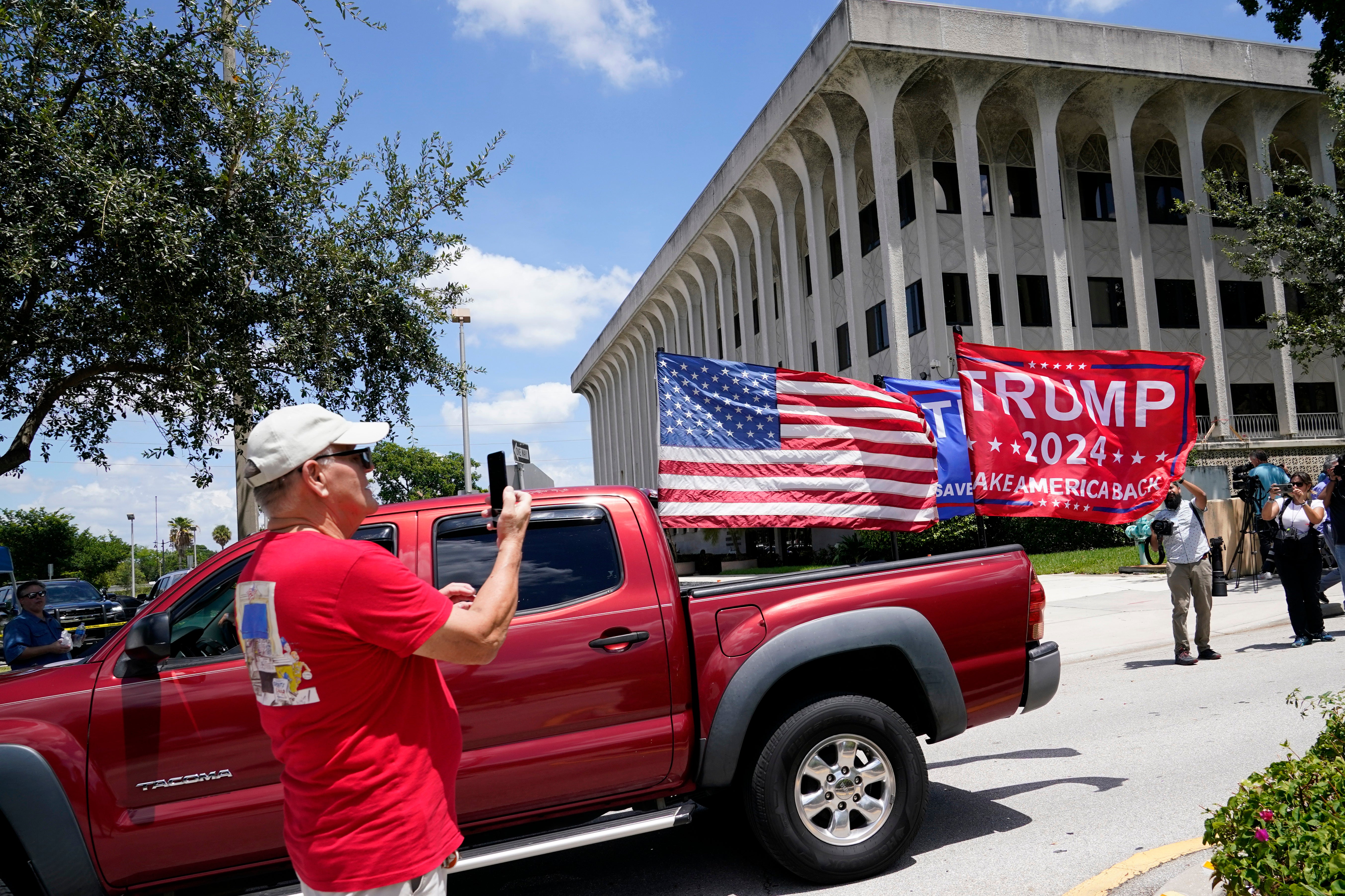 A vehicle with flags in support of Donald Trump drives outside of the Paul G. Rogers Federal Courthouse, Thursday, Aug. 18, 2022, in West Palm Beach, Fla