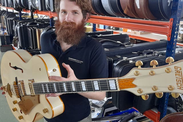 Auctioneer Luke Hobbs with the guitar Dave Grohl played on the Foo Fighters’ first hit videos (Gardiner Houlgate/PA)