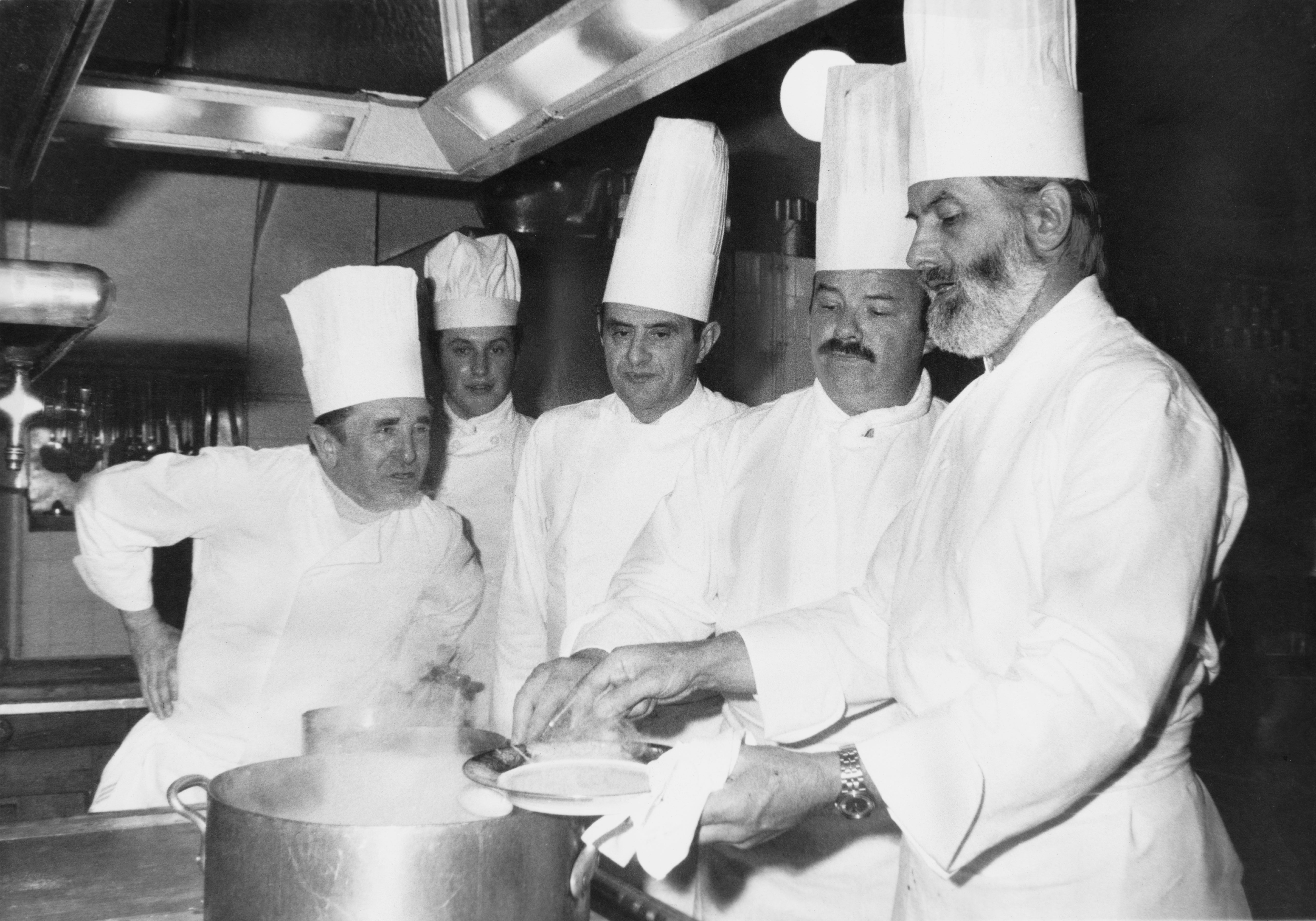 French chef Paul Bocuse (center) in the kitchens of the Elysee Palace, Paris, after being awarded the Legion of Honour by President Valery Giscard d’Estaing, on 25 February 1975. He is helping to prepare a presidential dinner with (left to right) Marcel Le Servot, Chef de cuisine at the Elysee Palace, Mathias Thery, Pierre Troisgros, and Jean Troisgros
