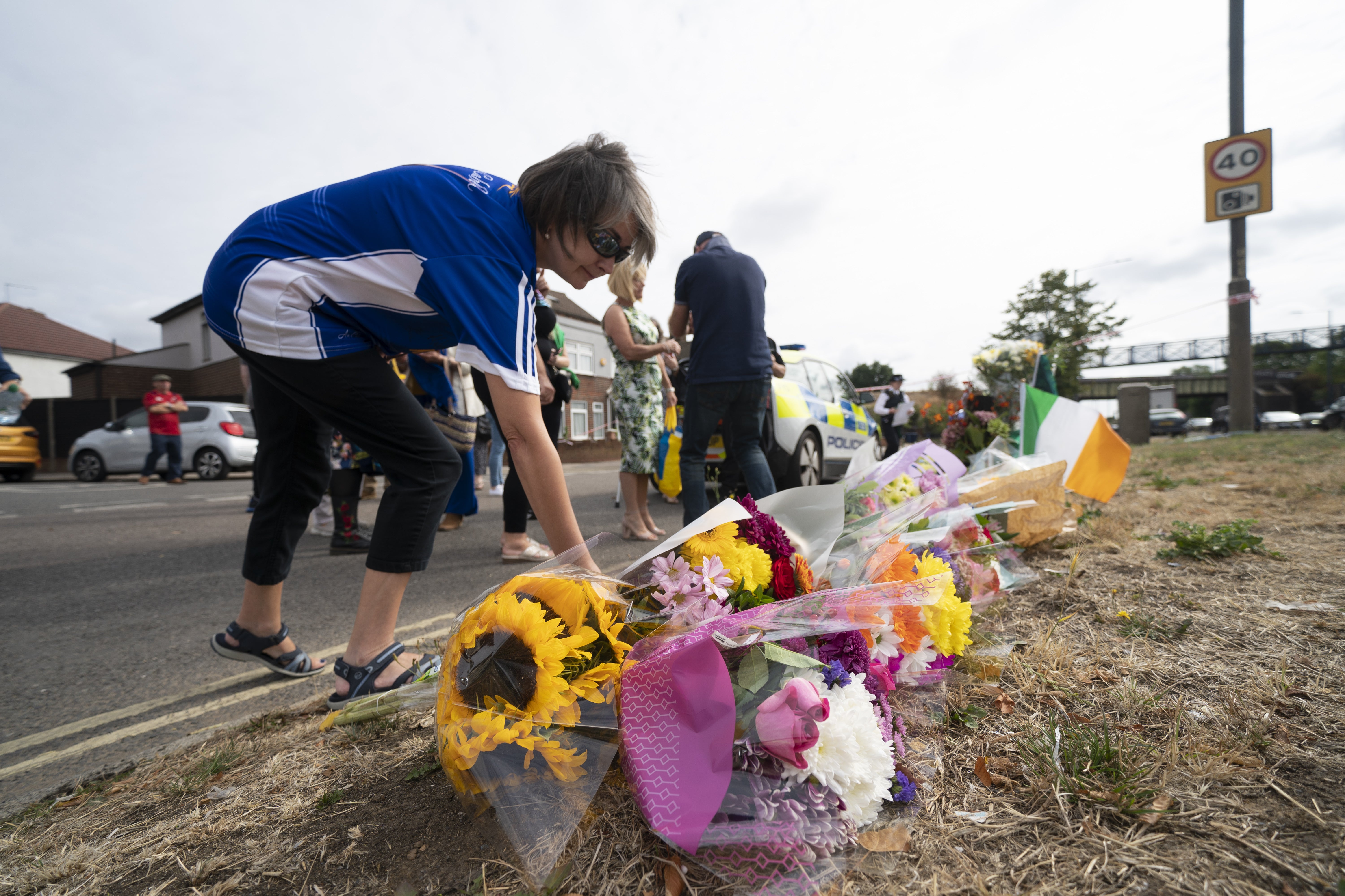 A woman lays flowers on Western Avenue Frontage Road in Greenford