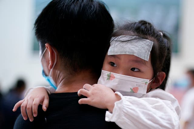 <p>A man carries a child wearing a face mask during Covid-19 outbreak in China</p>