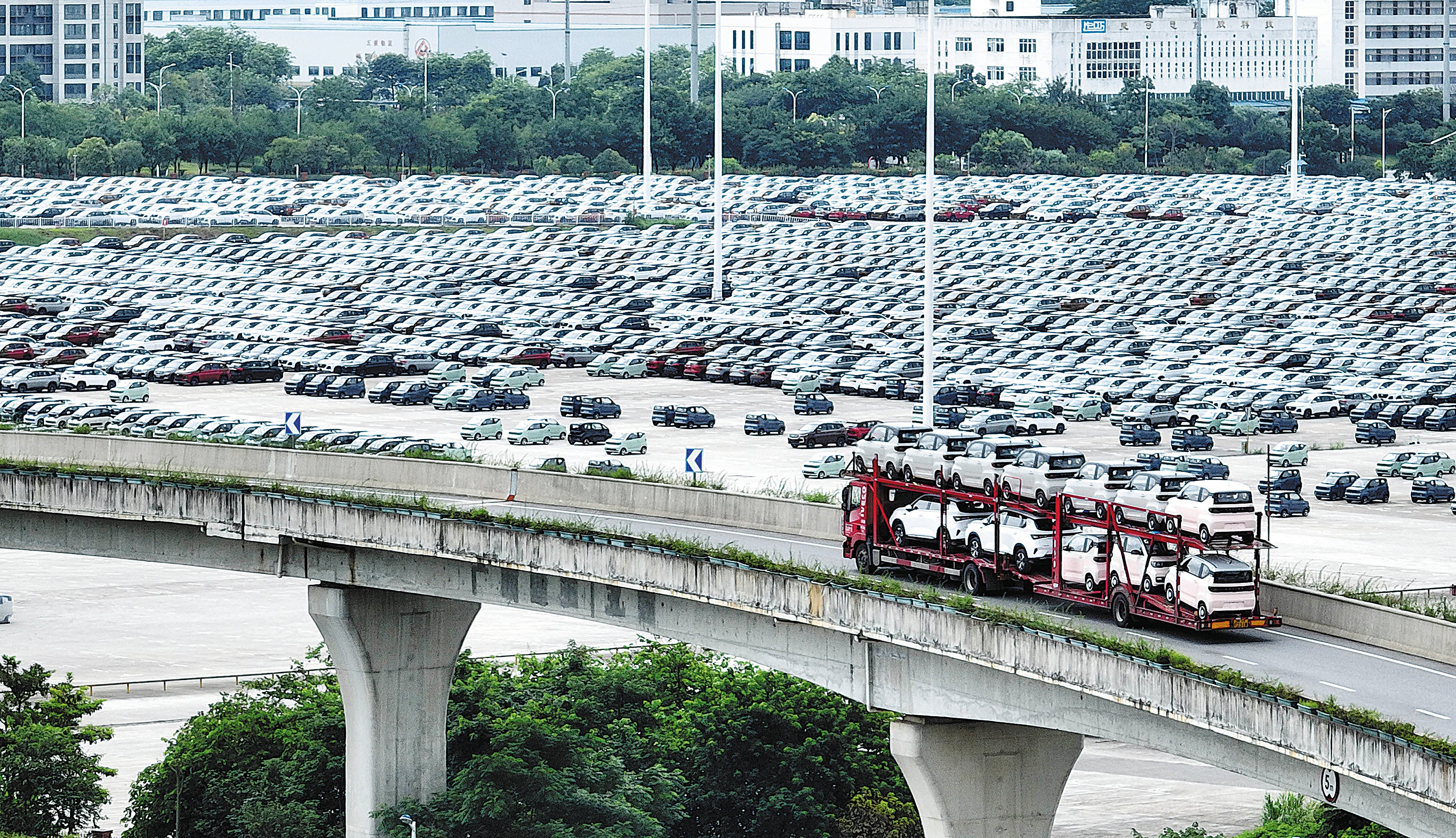 A truck loaded with new energy vehicles passes a logistics base in Liuzhou, Guangxi Zhuang autonomous region, on July 6