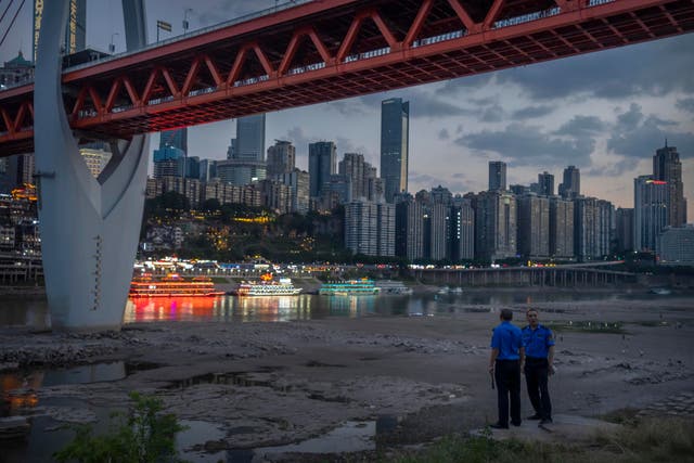 <p>Security officers stand on a hillside after clearing away visitors from the dry riverbed of the Jialing River, a tributary of the Yangtze, in southwestern China’s Chongqing Municipality</p>