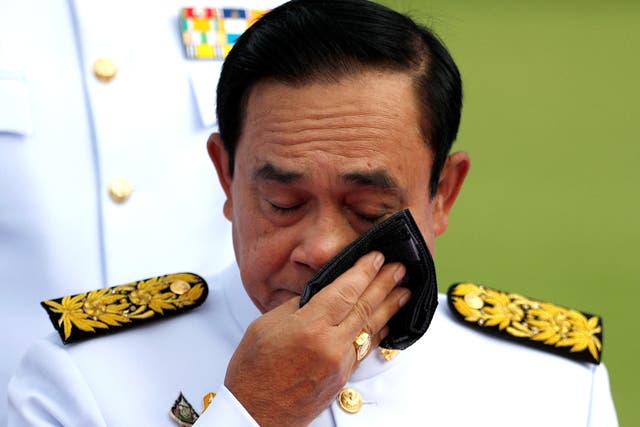 <p>Thailand’s prime minister Prayuth Chan-ocha wipes his face during a family photo session with new cabinet ministers at the Government House in Bangkok </p>