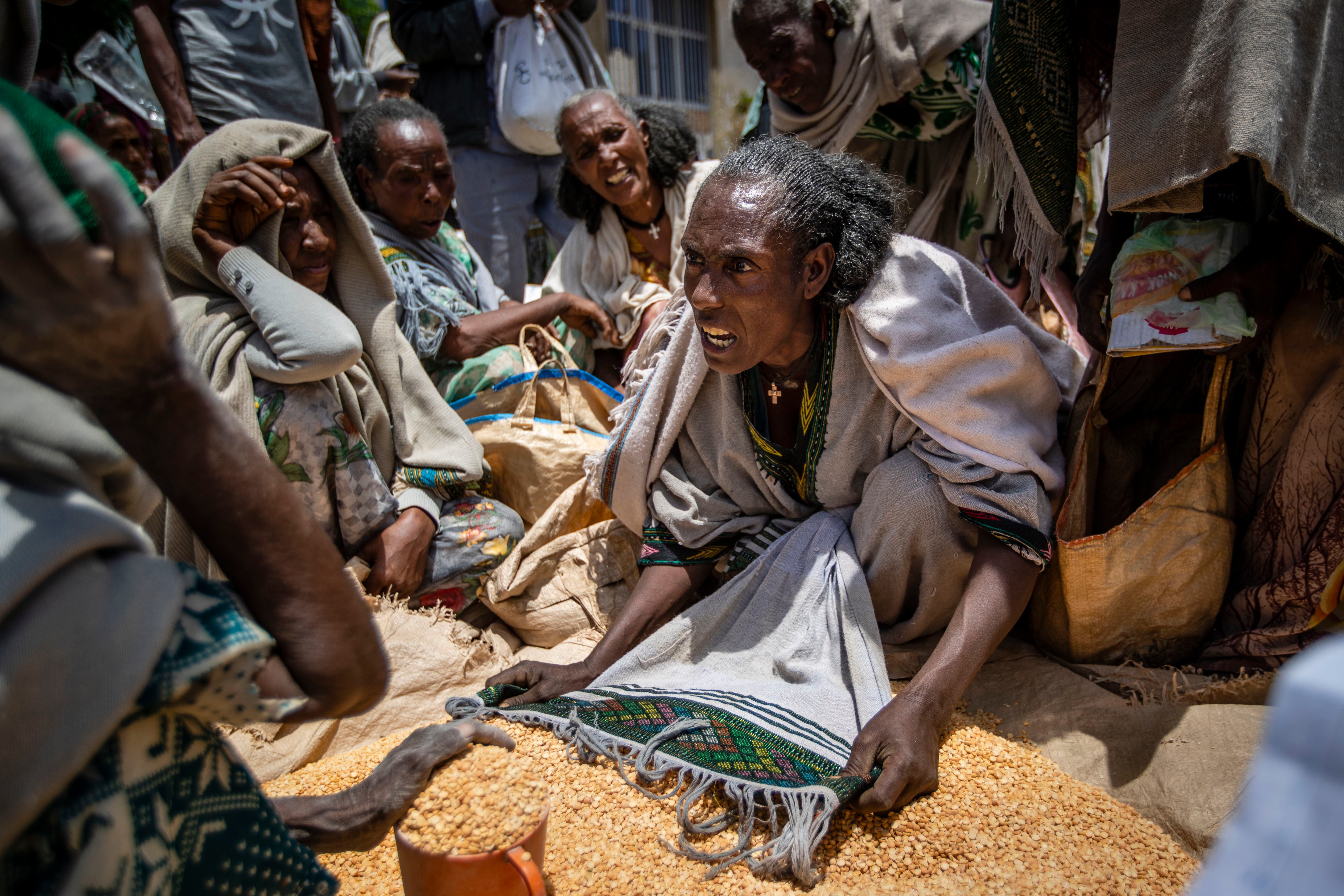 People negotiate the allocation of yellow split peas after they were distributed by the Relief Society of Tigray in the town of Agula