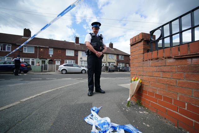 <p>A police officer lays flowers on Tuesday near the scene in Knotty Ash, Liverpool, where nine-year-old Olivia Pratt-Korbel was fatally shot</p>