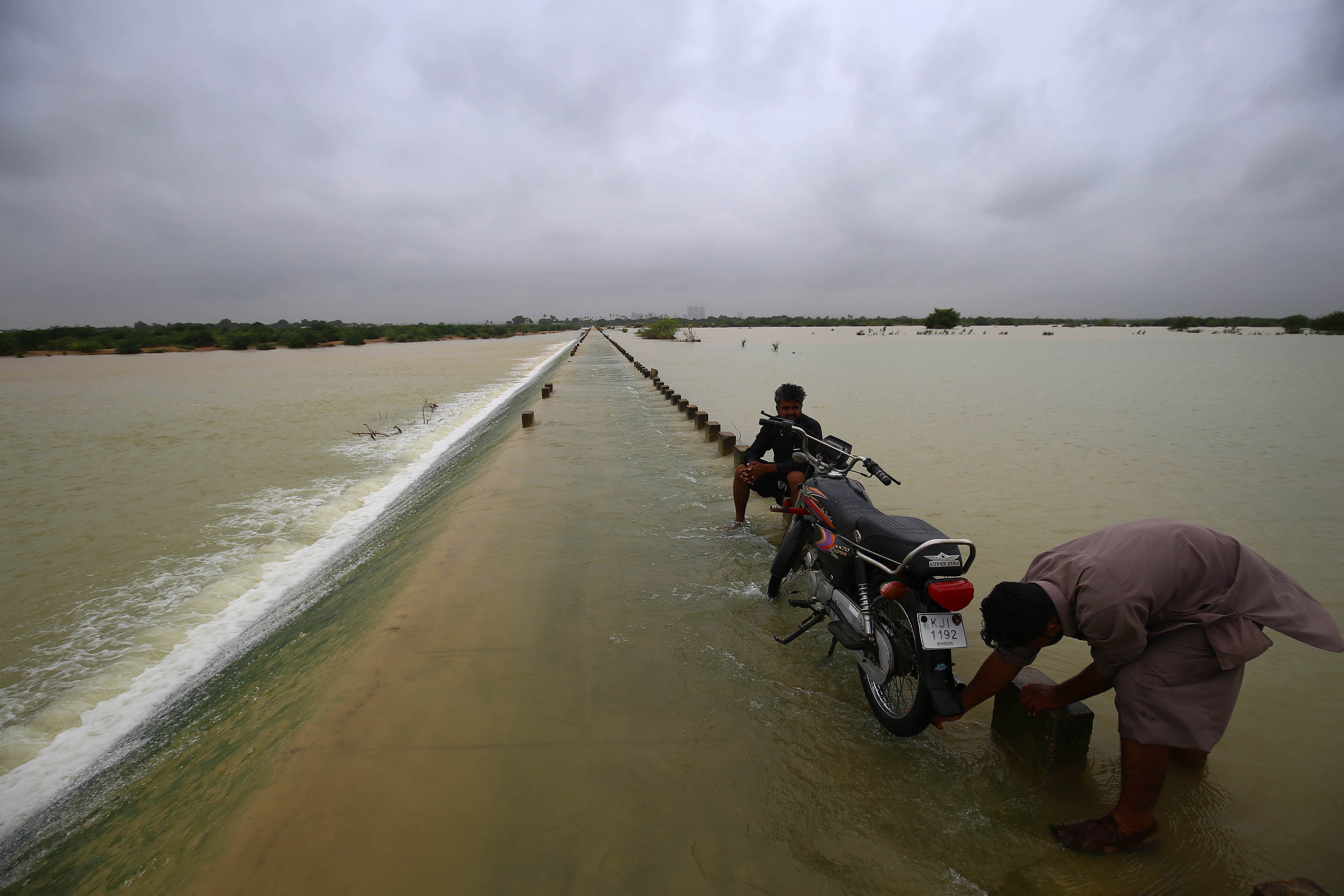 People make their ways through a flooded area following heavy rains in Karachi