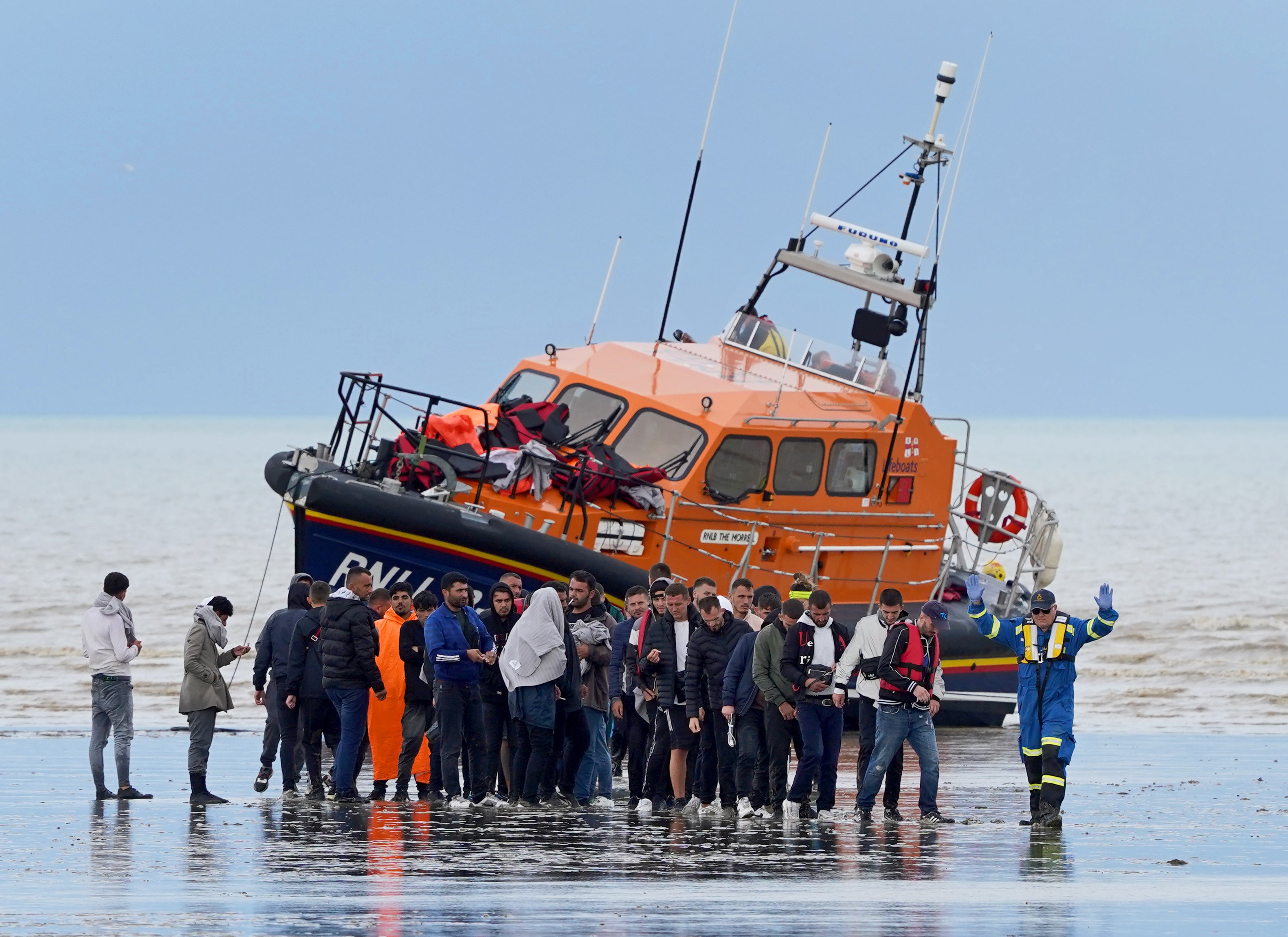 A group of people thought to be migrants walk ashore in Dungeness, Kent, after being intercepted by the Dungeness Lifeboat following a small boat incident in the Channel (Gareth Fuller/PA)