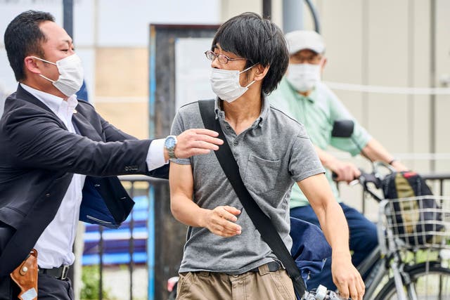 <p>Tetsuya Yamagami, center, holding a weapon, is detained where Shinzo Abe was shot, western Japan on 8 July 2022 </p>