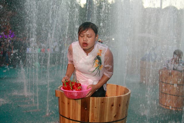 <p>People eat peppers standing on ice buckets during a competition at Song Dynasty town as ground temperature remain around 40 degrees Celsius many parts of China</p>