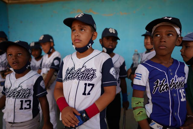 <p>Children from the Downtown Havana baseball team listen to instructions from a coach during a match</p>