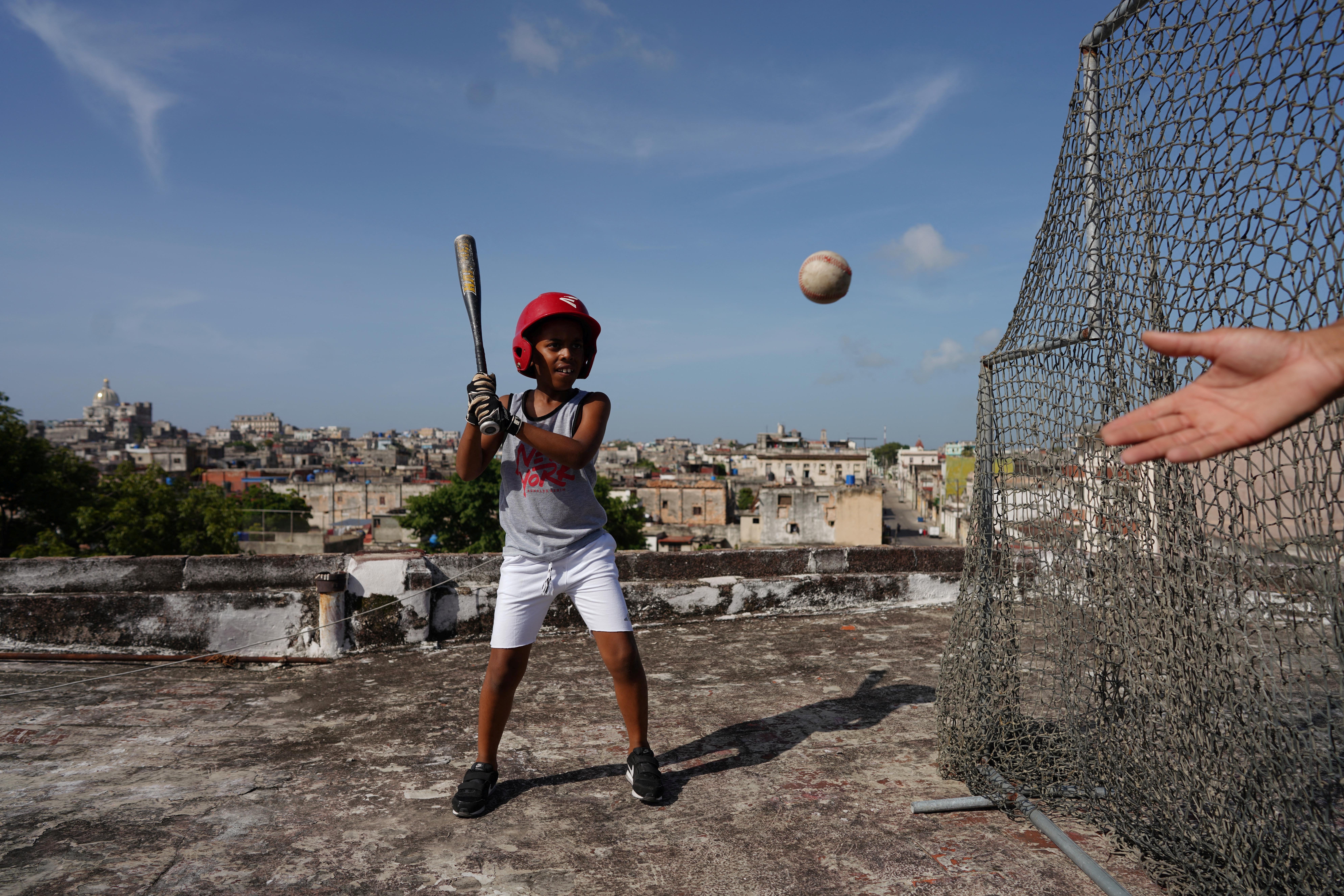 Baseball fan Kevin Kindelan, eight, practises with his father on the roof of their house in Havana