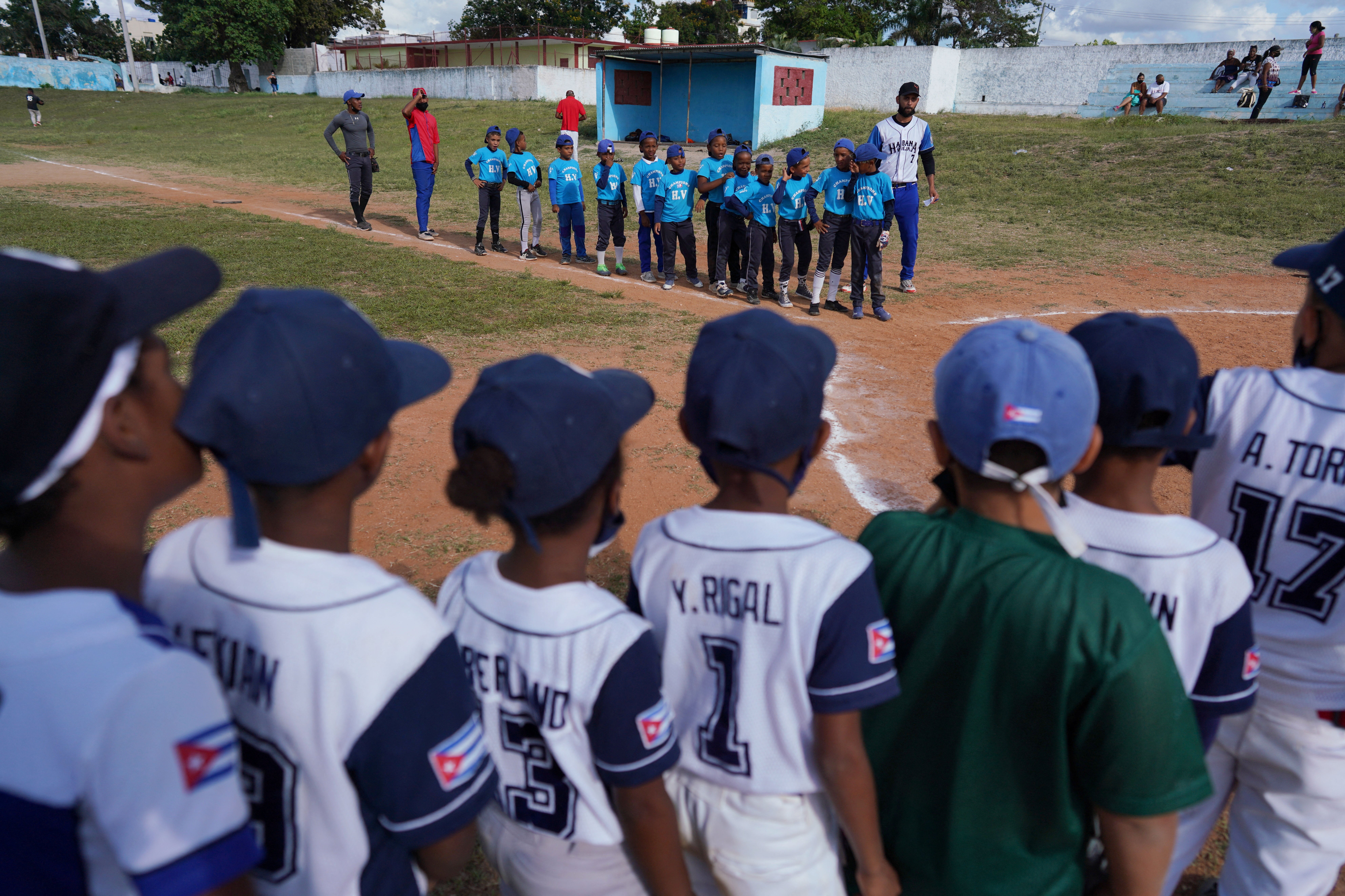Children from the Downtown Havana baseball team prepare to high five the Champions team after a match in Havana