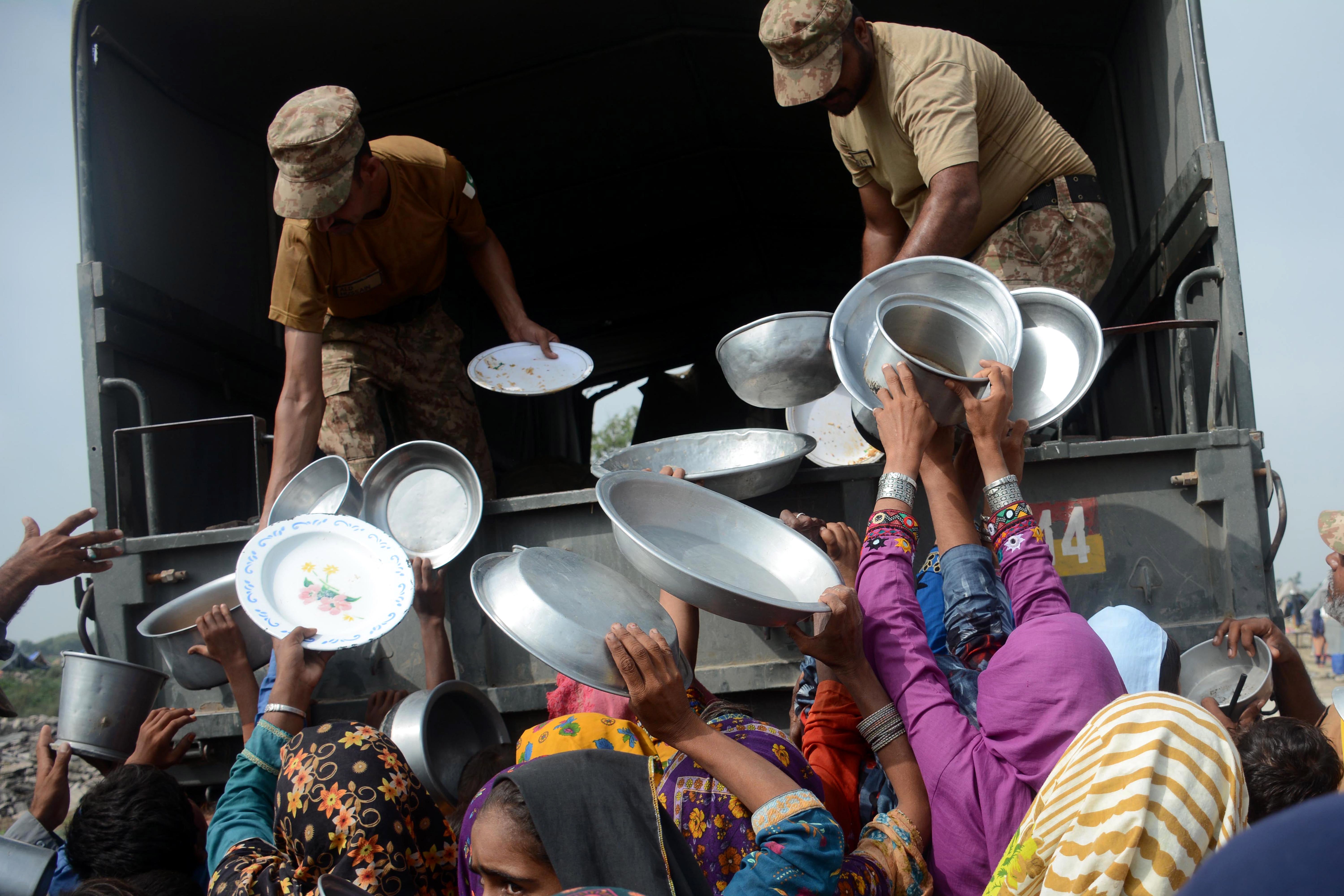 Pakistani army soldiers distribute food to flood-affected people in Rajanpur, Punjab province on Saturday