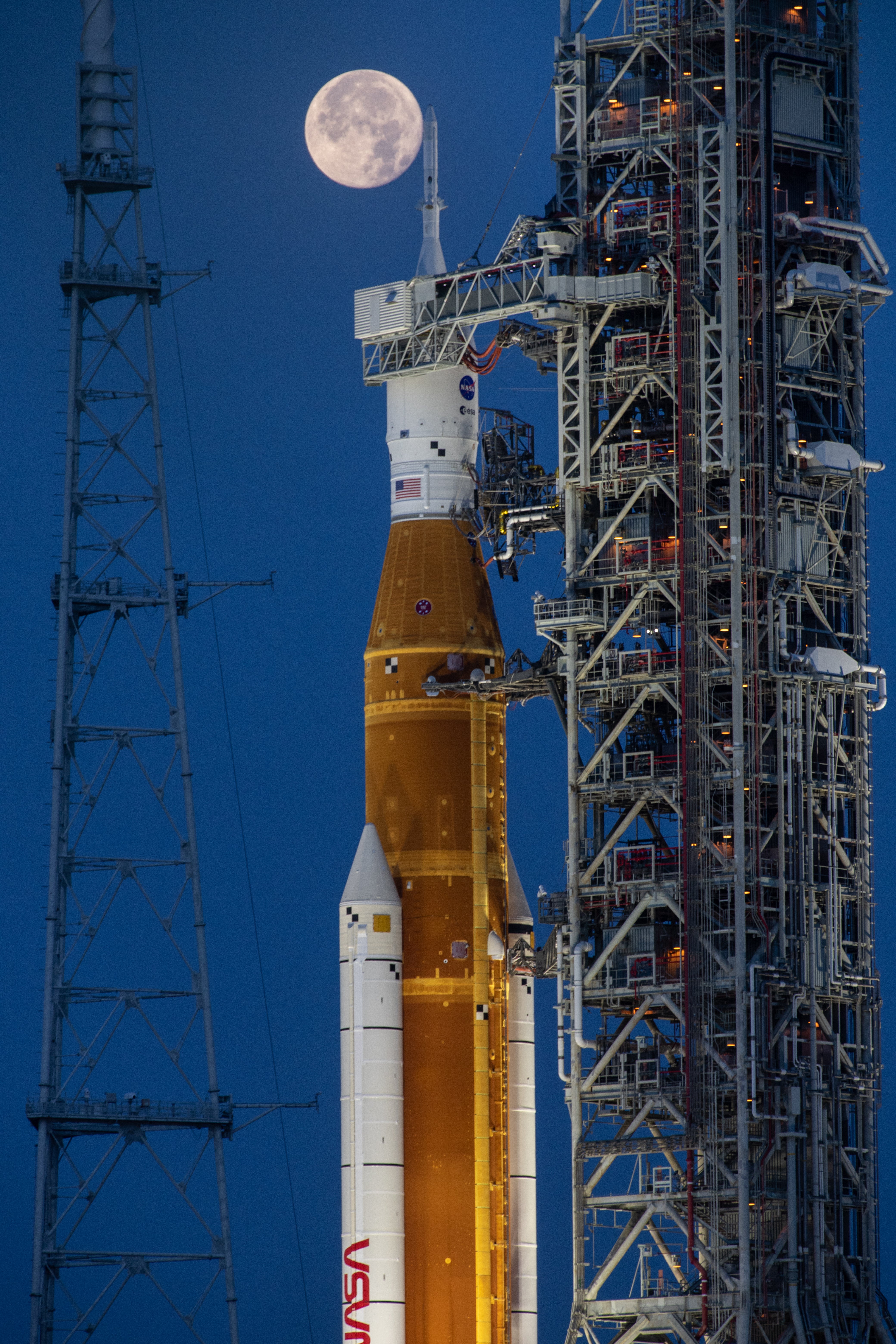 Nasa’s SLS Moon rocket and the Orion spacecraft on the launch pad beneath a full Moon