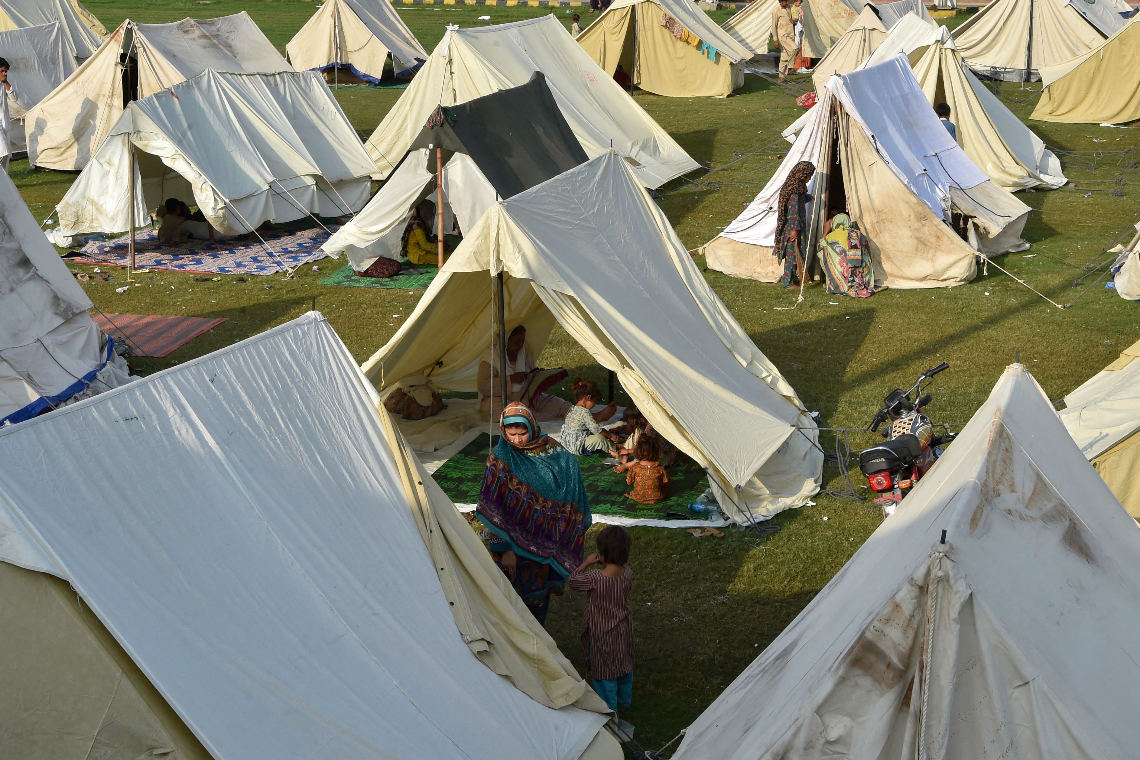 Displaced people sit in their tents at a makeshift camp after fleeing from their flood-hit homes following heavy monsoon rains in Charsadda