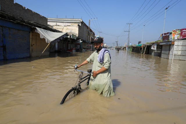 <p>A man walks with a bicycle in flood water following rains and floods during the monsoon season in Nowshera, Pakistan </p>