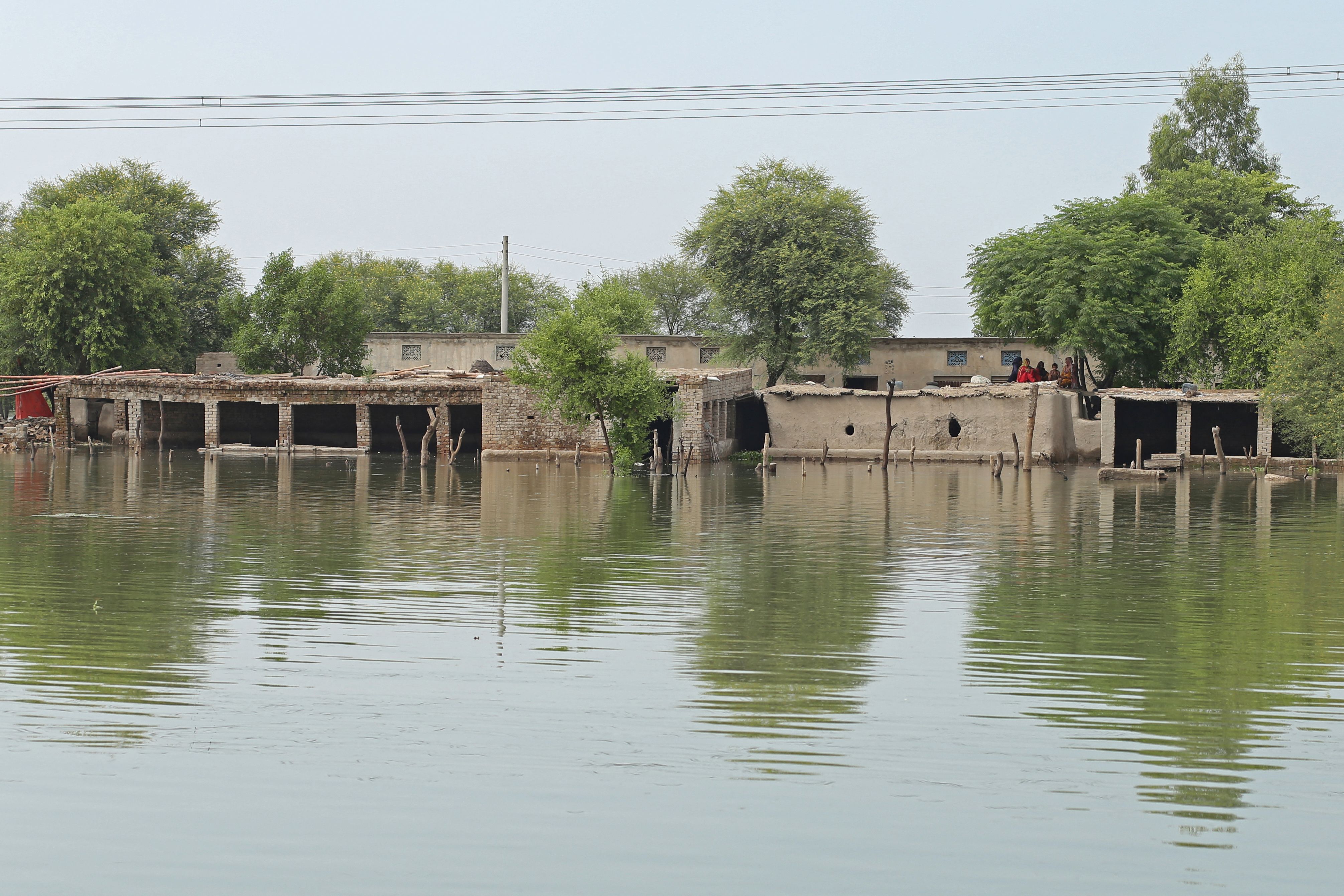 Women sit atop their mud house in Dera Ghazi Khan hit area following heavy monsoon rains