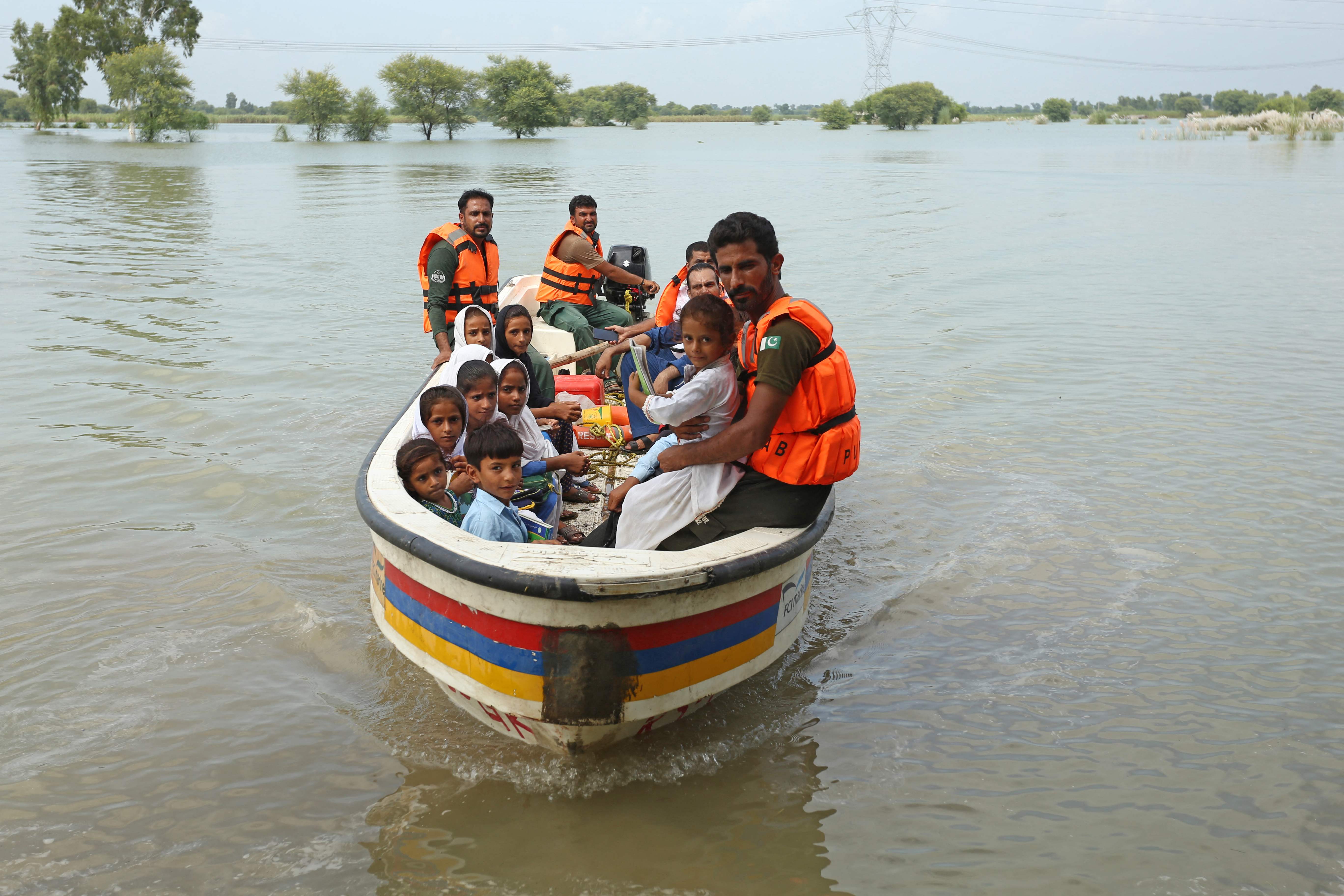 Rescue workers use a boat to drop children back home after school in a flood hit area following heavy monsoon rains in Dera Ghazi Khan