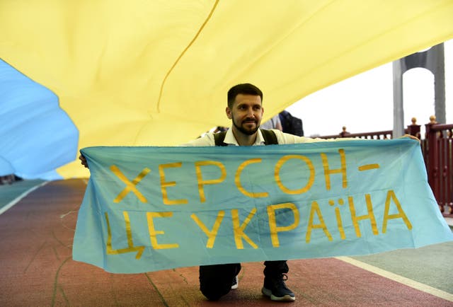 <p>A man carries a banner with the words ‘Kherson in Ukraine’</p>