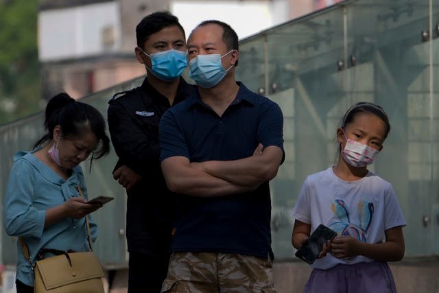 <p>Residents wearing face masks wait in line to get their routine COVID-19 throat swabs at a coronavirus testing site in Beijing </p>