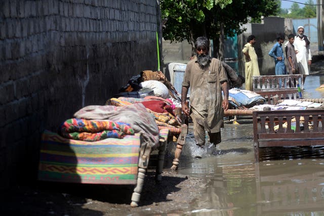 <p>A man wade through a flooded area after heavy rains, in Charsadda, Pakistan</p>