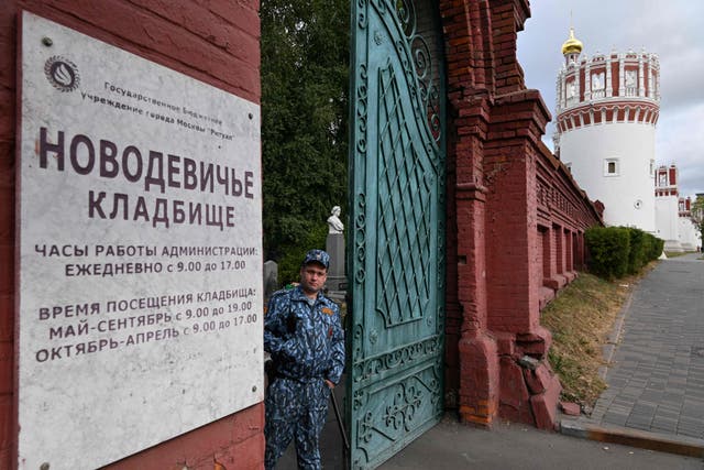 <p>A security guard stands at the gate of the Novodevichy Cemetery in Moscow</p>
