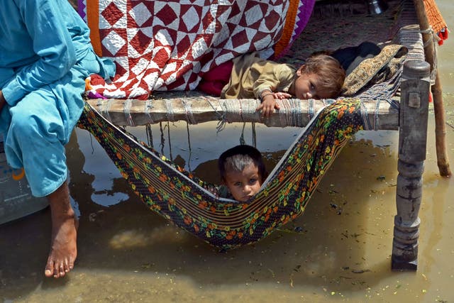 <p>Flood-affected children sit on a traditional cot alongside flood waters after heavy monsoon rains in the Jaffarabad district of Balochistan province on 31 August </p>