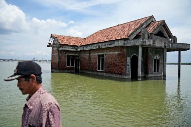 <p>A man walks past a house abandoned after it was inundated by water due to the rising sea level in Sidogemah, Central Java, Indonesia, in November 2021. </p>