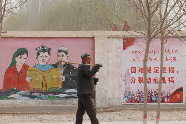 <p>File: A man walks past government propaganda depicting ethnic minority residents reading the constitution </p>