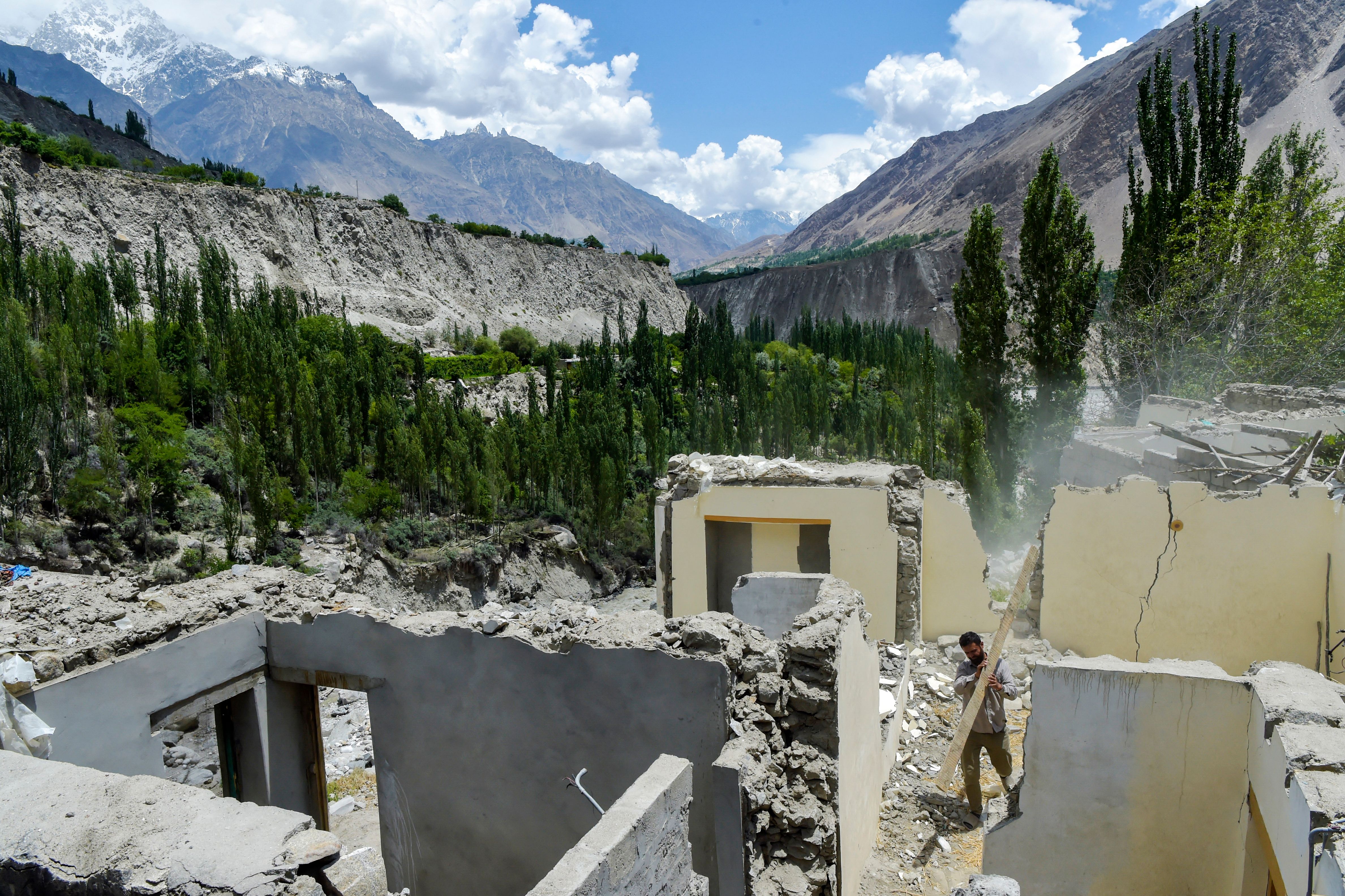 A resident clears debris from a damaged house after a lake outburst because of a melting glacier in Hassanabad village of Pakistan’s Gilgit-Baltistan region in June this year