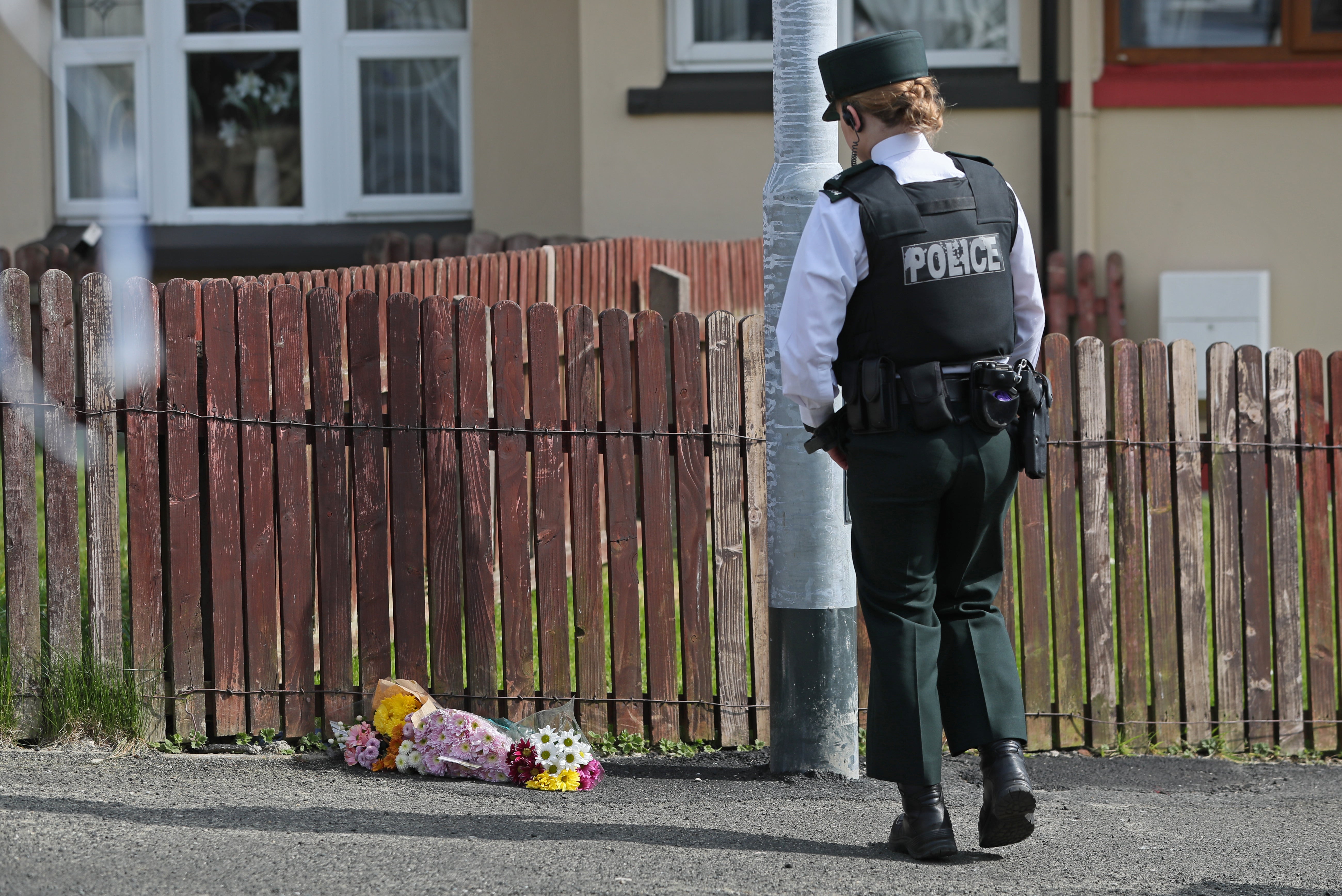 A police officer lays flowers at the scene of Lyra McKee’s shooting in Creggan in 2019 (PA)