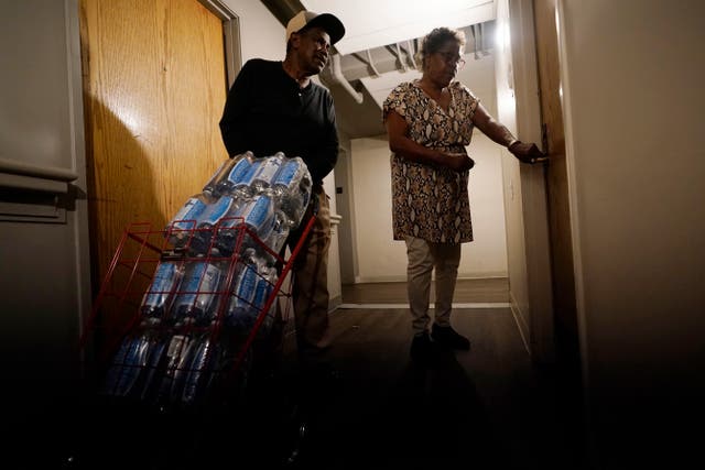 <p>Mary Gaines, right, a resident of the Golden Keys Senior Living apartments, unlocks her door as a friend helps her with cases of fresh water in Jackson</p>