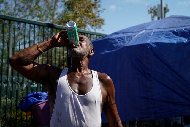 Un hombre se mantiene hidratado mientras el extremo golpea Los Ángeles, California el jueves