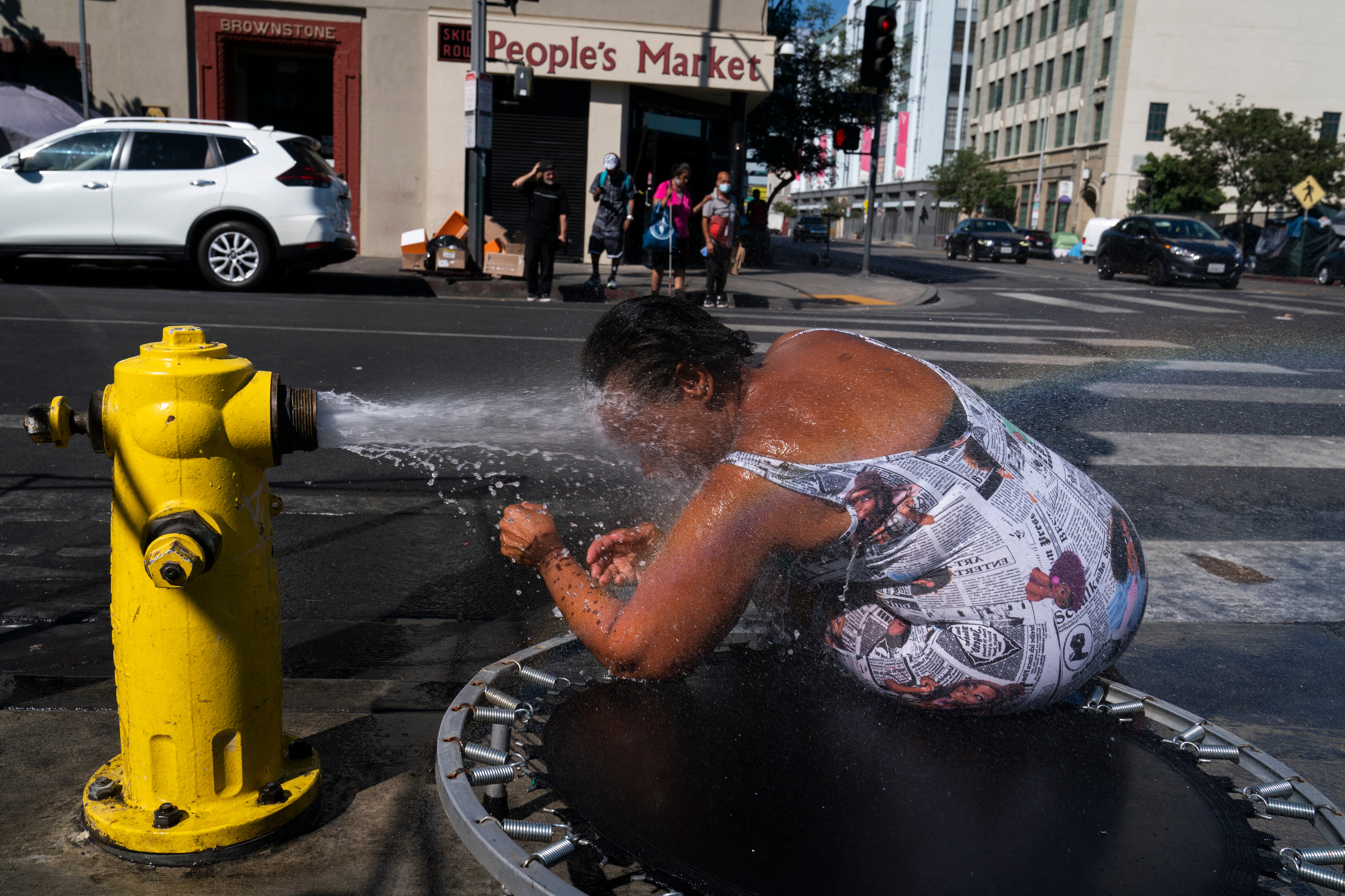 Stephanie Williams, 60, cools off with water from a hydrant in the Skid Row area of Los Angeles during the current heatwave